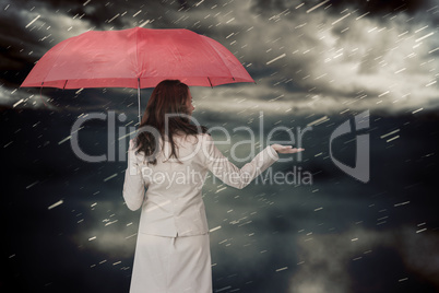 Composite image of businesswoman holding umbrella