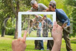 Composite image of hand holding tablet pc