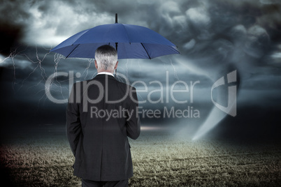 Composite image of businessman holding umbrella