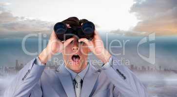Composite image of suprised businessman looking through binocula