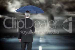 Composite image of businessman holding umbrella