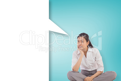 Composite image of businesswoman sitting cross legged thinking w