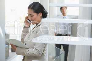 Estate agent talking on phone with buyer in background
