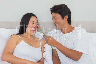 Man touching his girlfriends nose with red rose