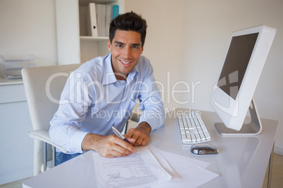 Casual businessman sitting at desk writing