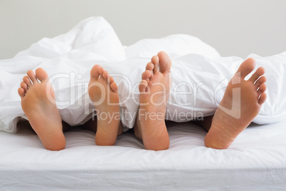 Couples feet sticking out from under duvet