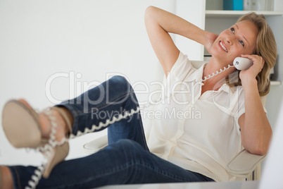 Casual businesswoman sitting at her desk with feet up on the pho