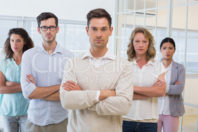 Casual business team frowning at camera with arms crossed