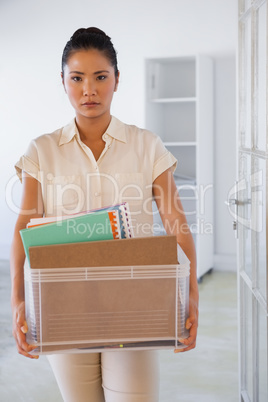 Fired businesswoman holding box of her things