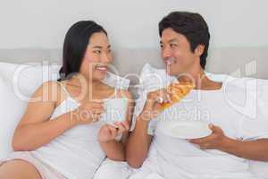 Happy couple having breakfast in bed