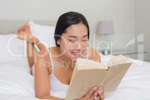 Smiling woman lying on bed reading