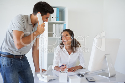 Casual business team laughing together at desk