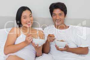 Happy couple having breakfast in bed