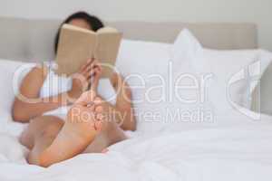 Woman lying on bed reading