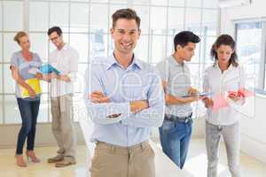 Casual boss smiling at camera in front of business team