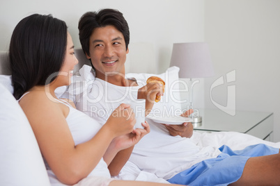 Happy couple having breakfast in bed