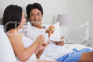 Happy couple having breakfast in bed