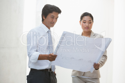 Estate agent and buyer looking at blueprint