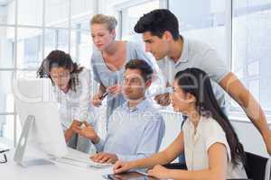 Casual businessman showing colleagues something on computer