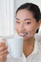 Smiling woman sitting on couch having coffee