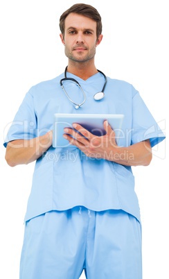 Handsome surgeon in blue scrubs using tablet pc