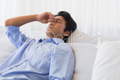 Man sitting on couch with a headache