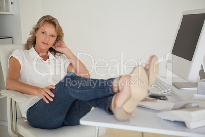 Casual businesswoman sitting at her desk with feet up