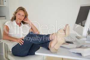 Casual businesswoman sitting at her desk with feet up