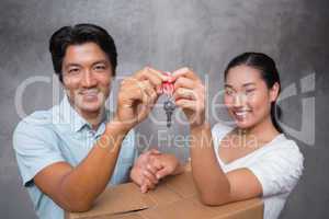 Happy couple holding house key and leaning on moving box