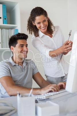 Casual business team looking at computer together at desk