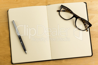Overhead of open notebook with pen and glasses