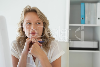 Casual businesswoman thinking at her desk