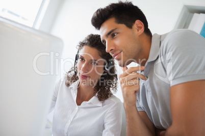 Casual businessman looking at colleagues computer