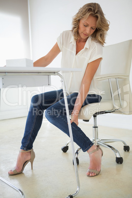 Casual businesswoman touching her ankle