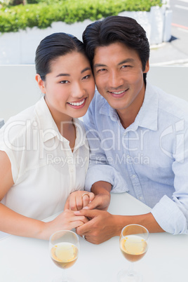 Happy couple holding hands and having white wine