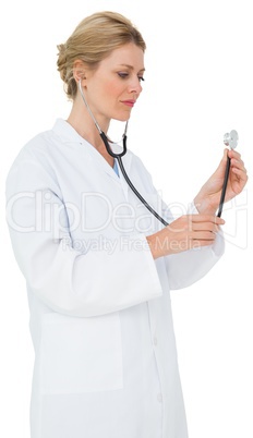 Blonde doctor in lab coat listening with stethoscope