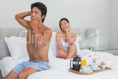 Smiling woman watching her boyfriend yawn and stretch