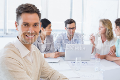 Casual businessman smiling at camera during meeting