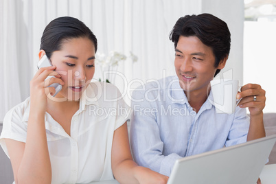 Couple using laptop with woman talking on phone