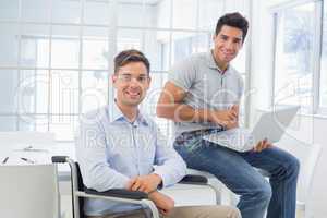 Casual businessman in wheelchair working with colleague