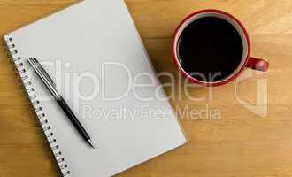 Overhead of notebook with pen and coffee