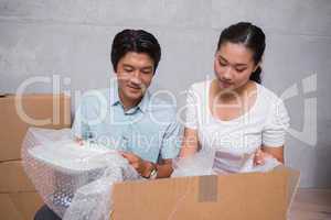 Happy couple sitting on floor unpacking boxes