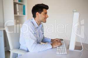 Casual businessman typing at his desk