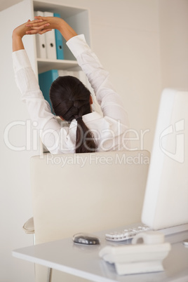 Casual businesswoman stretching at her desk