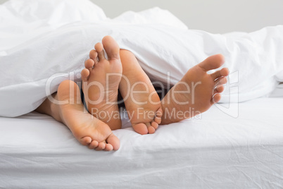 Couples feet sticking out from under duvet