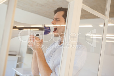 Casual businessman shouting through megaphone