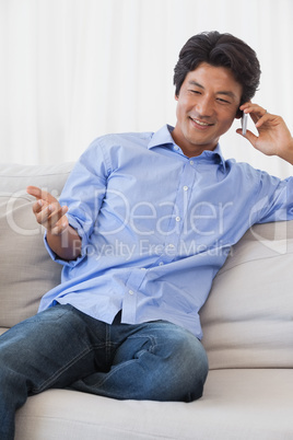 Happy man sitting on couch on the phone