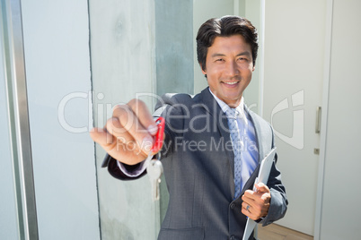 Confident estate agent standing at front door showing key