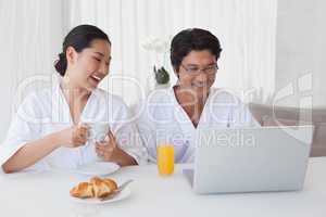 Happy couple using laptop over breakfast