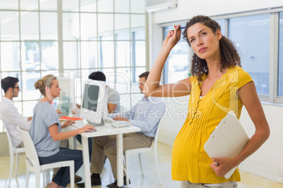 Casual pregnant businesswoman standing and thinking